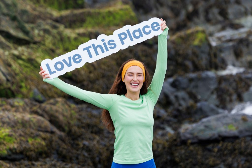 Rozanne Purcell holding a love this place banner above her head